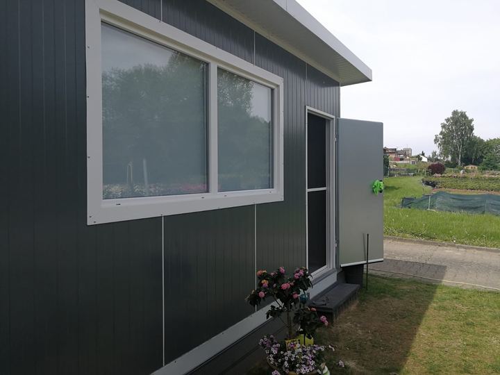 Von Frigano realisierter Bürocontainer aus Isolierpaneelen als Gartenbüro mit großem Fenster und offener Tür
