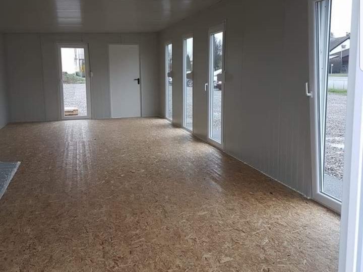 Innenraum eines von Frigano realisierten Bürocontainers mit großen Fenstern und OSB-Boden