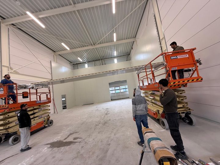 Monteure bei der Paneelmontage eines Kühlhauses mit Hubarbeitsbühnen