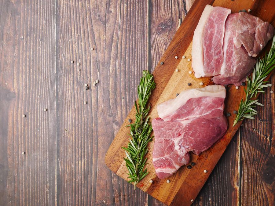 Rohe Schweinefleischscheiben auf einem Holzbrett